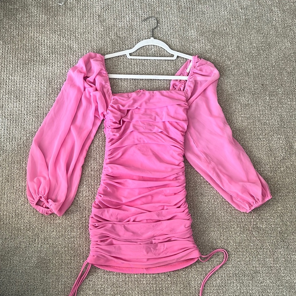 Pink tight mini dress, slightly sheer long sleeve, ties on the bottom sides